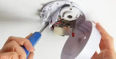 Certified technician wiring smoke detector during installation in Baltimore, MD